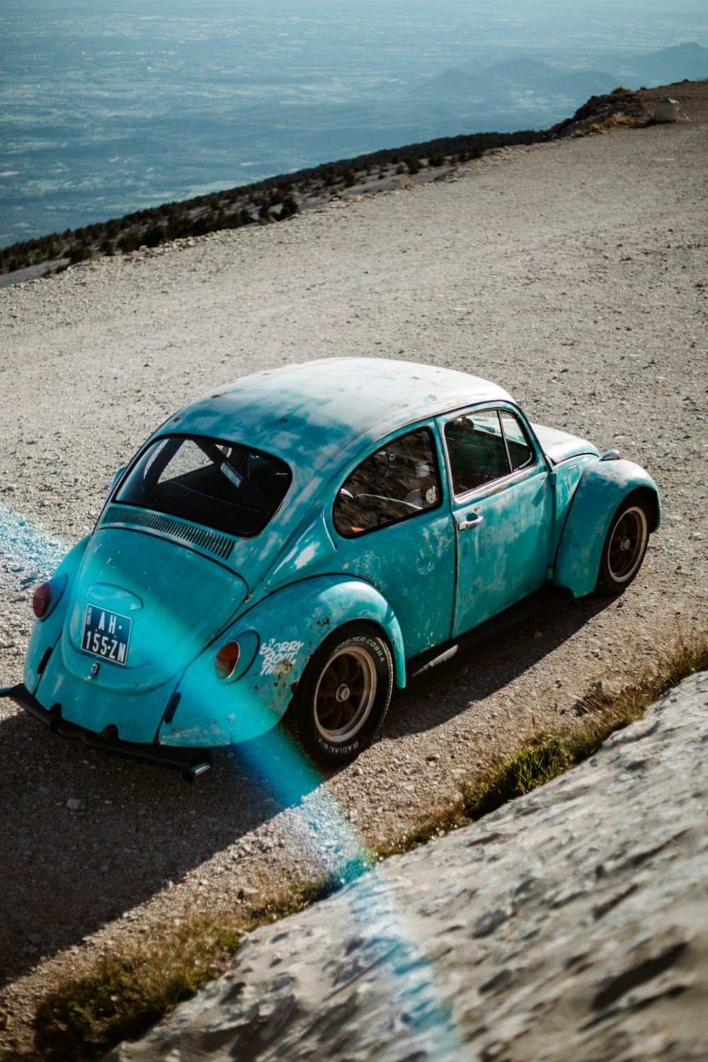 teal volkswagen beetle on gray sand during daytime