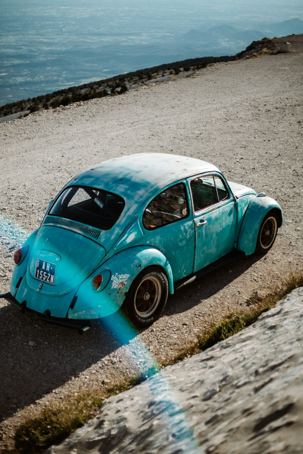 Besouro volkswagen azul-petróleo na areia cinzenta durante o dia