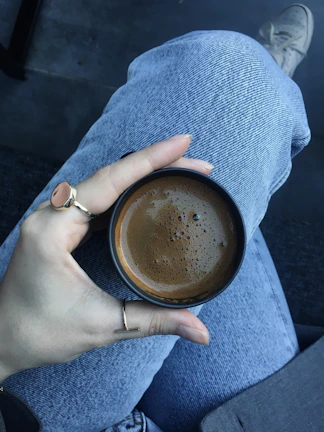 Stacked rings on a hand holding a coffee cup on a bustling city street.