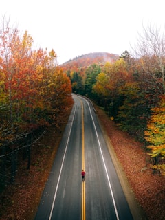 person in black jacket walking on the road during daytime