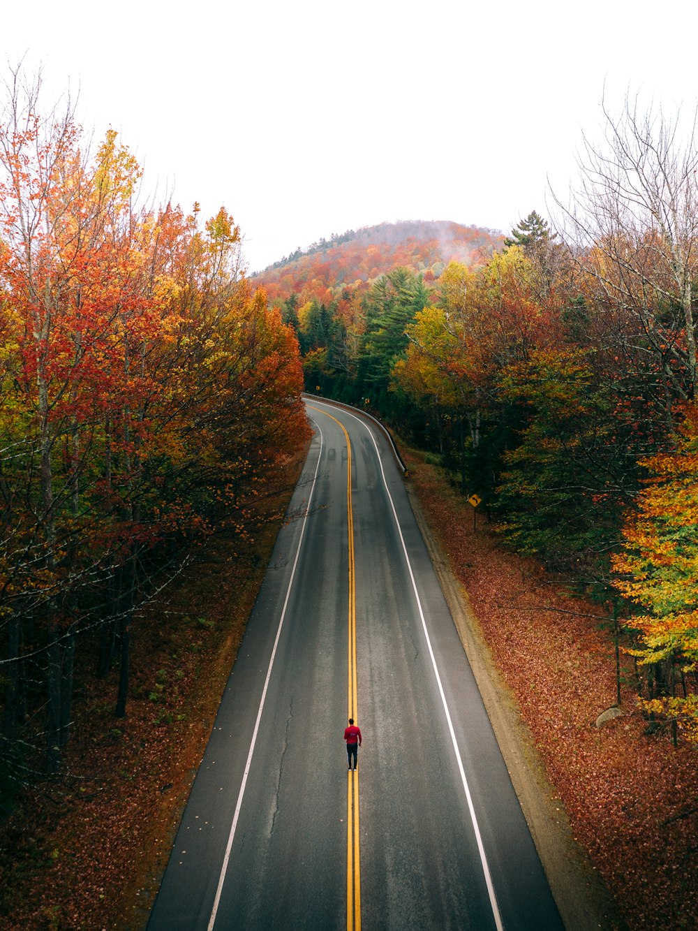 Personne en veste noire marchant sur la route pendant la journée