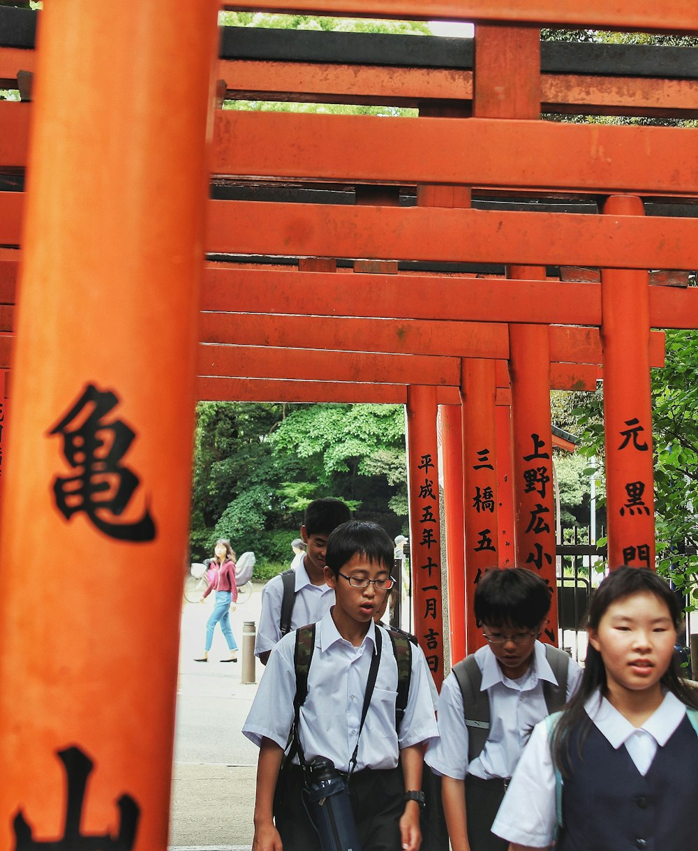 a group of children walking under an orange structure