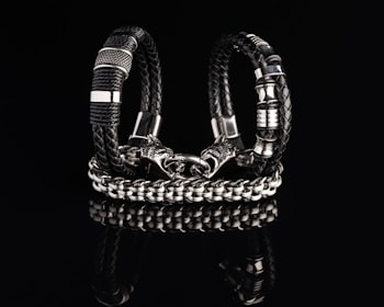 A rugged men's wrist adorned with a braided leather bracelet and a silver clasp.