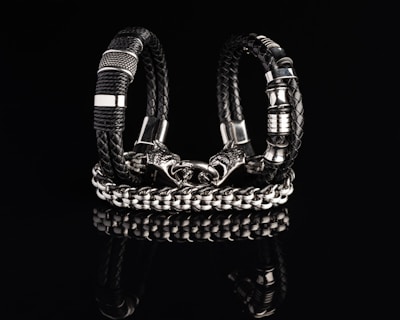 Dark leather bracelet adorned with Nordic symbols and silver accents on a black surface