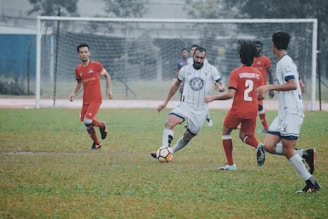 group of men playing soccer on green grass field during daytime