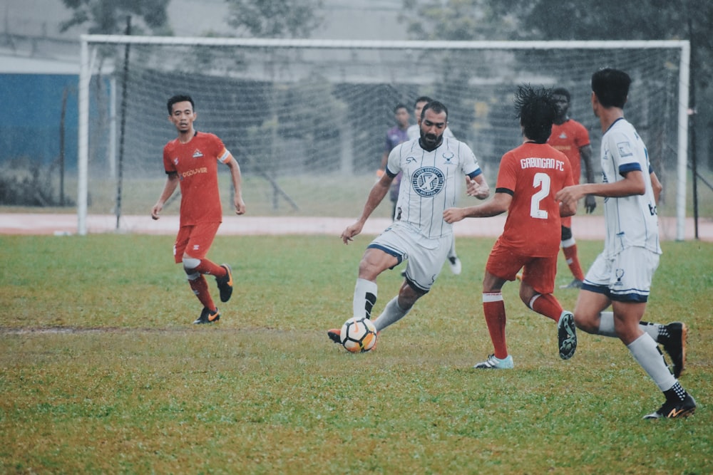 group of men playing soccer on green grass field during daytime