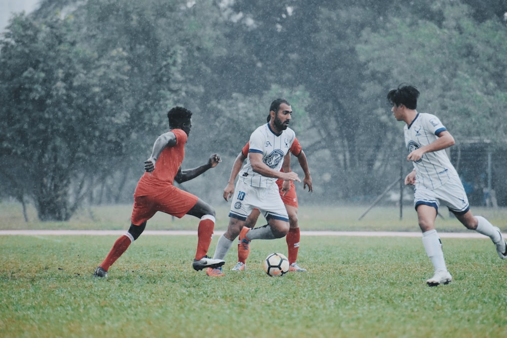 men playing soccer on green grass field during daytime