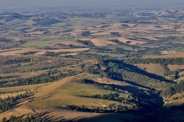 Aerial view of a sprawling rural property with rolling hills and dense tree lines.