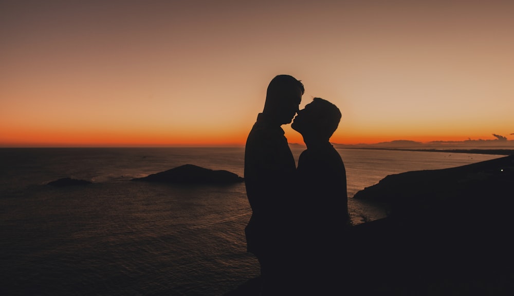 silhouette of couple kissing on beach during sunset