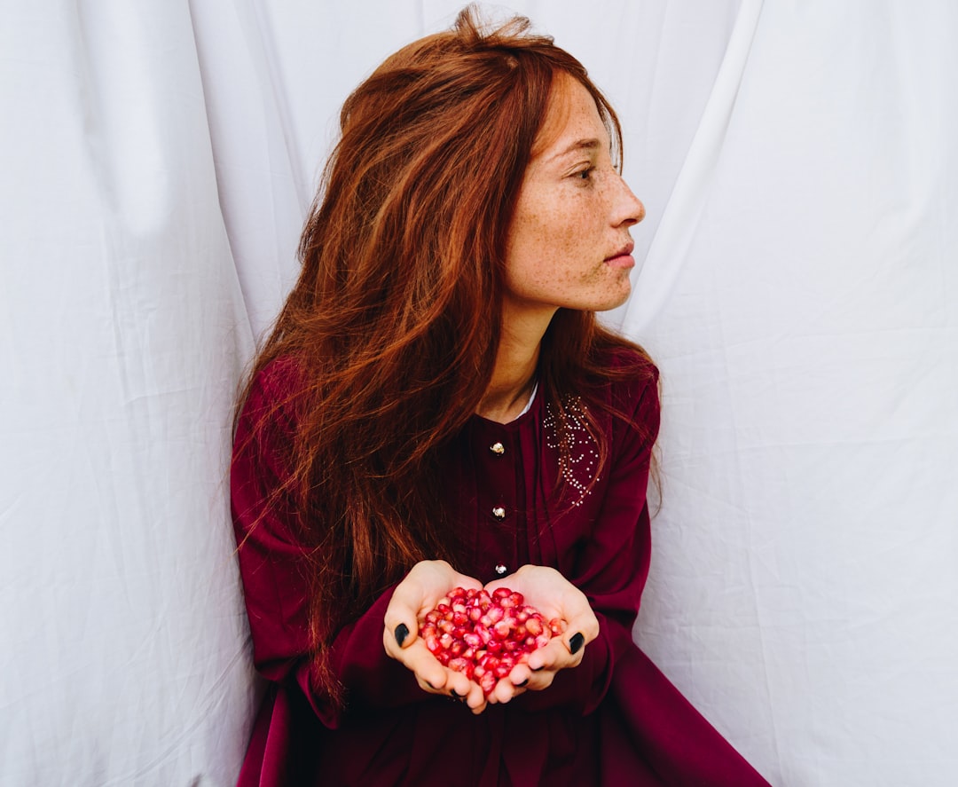 woman in red long sleeve shirt holding white and red flower bouquet