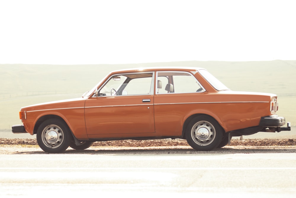 orange sedan on white sand during daytime