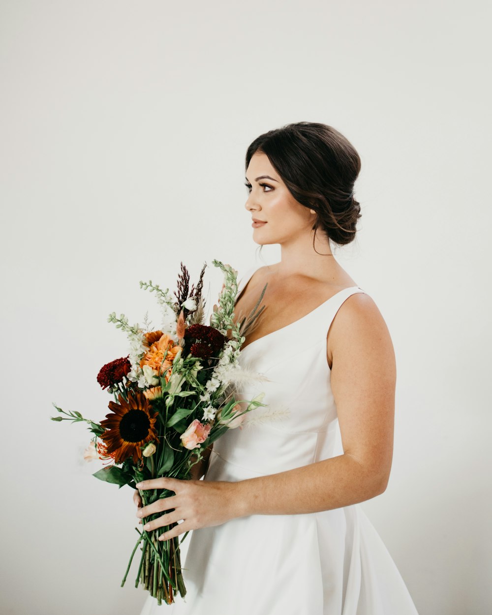 woman in white tank top holding bouquet of flowers