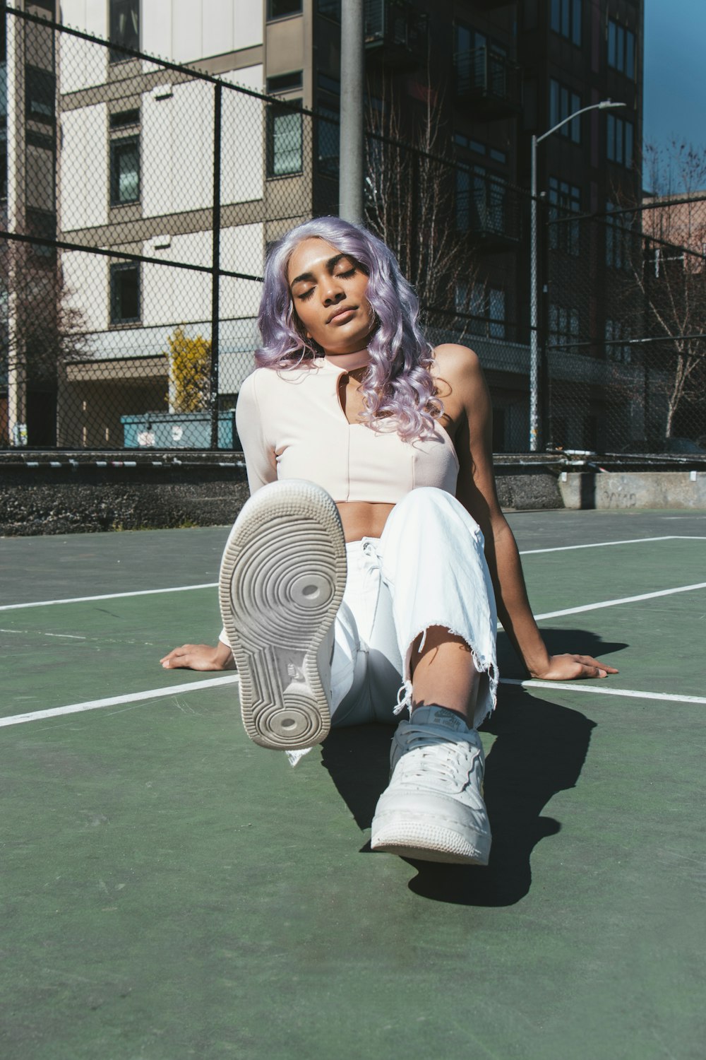 woman in white tank top and white shorts sitting on basketball court