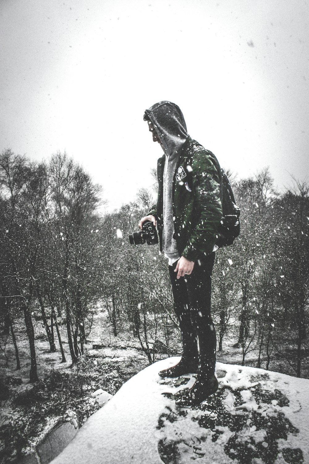 Mann in schwarzer Jacke und Hose steht auf schneebedecktem Boden