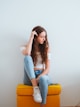 woman in blue denim jeans sitting on yellow chair