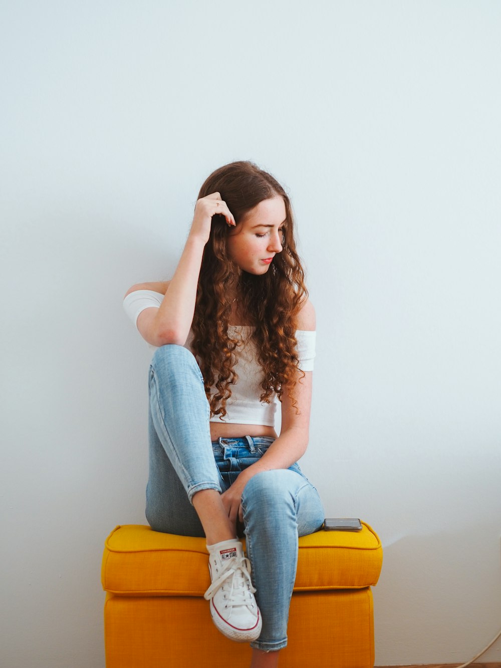 femme en jean bleu assis sur une chaise jaune