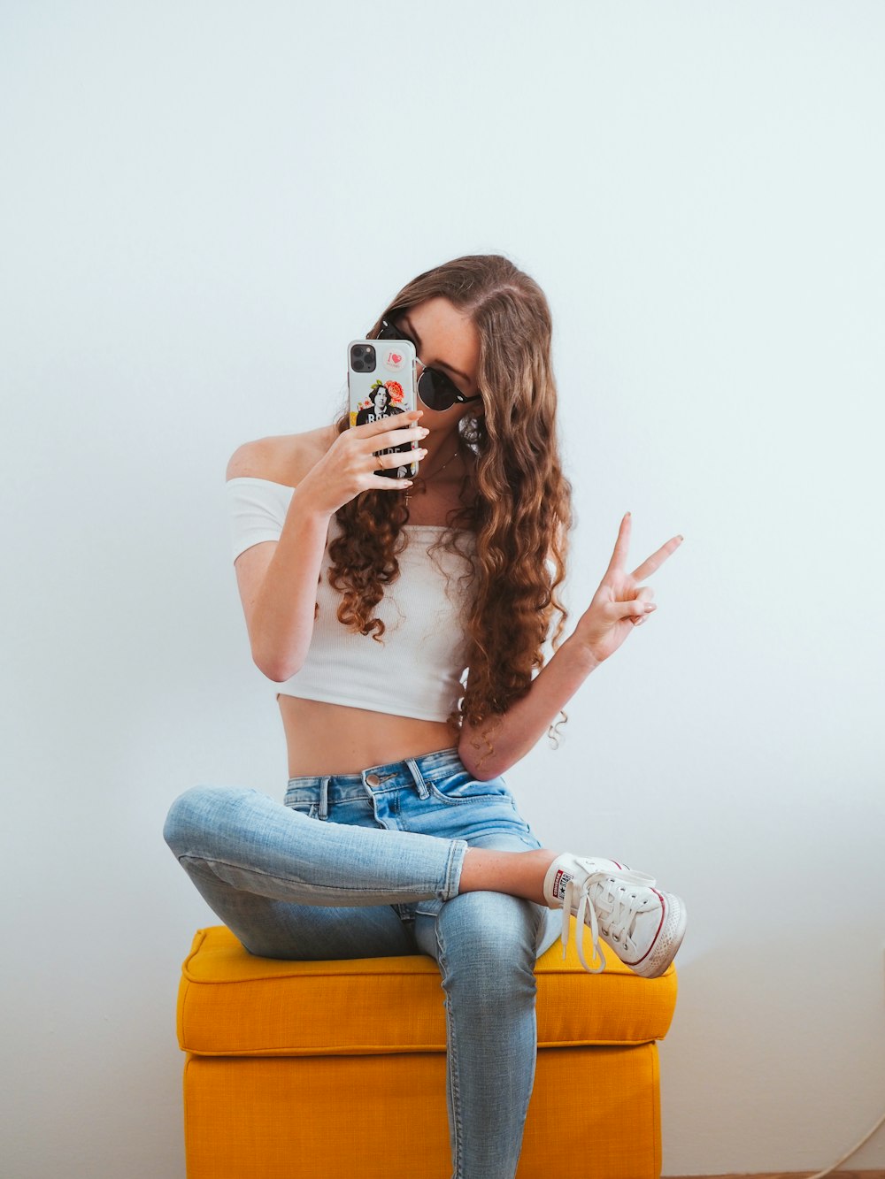 Frau in rosa Tanktop und blauer Jeans sitzt auf gelbem Stuhl