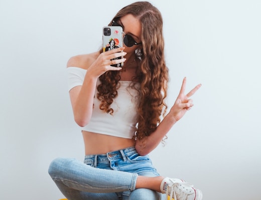 woman in pink tank top and blue denim jeans sitting on yellow chair