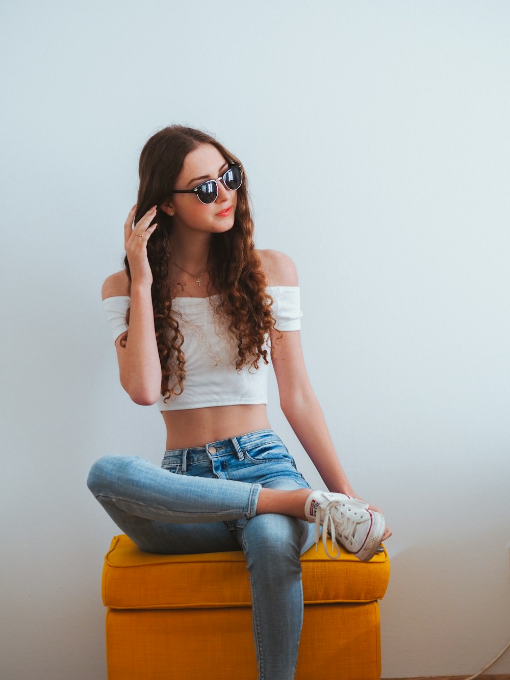 Donna in crop top bianco e jeans denim blu che indossano occhiali da sole neri