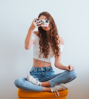 woman in pink long sleeve shirt and blue denim jeans sitting on white floor