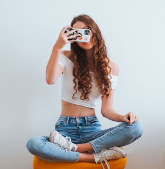 woman in pink long sleeve shirt and blue denim jeans sitting on white floor