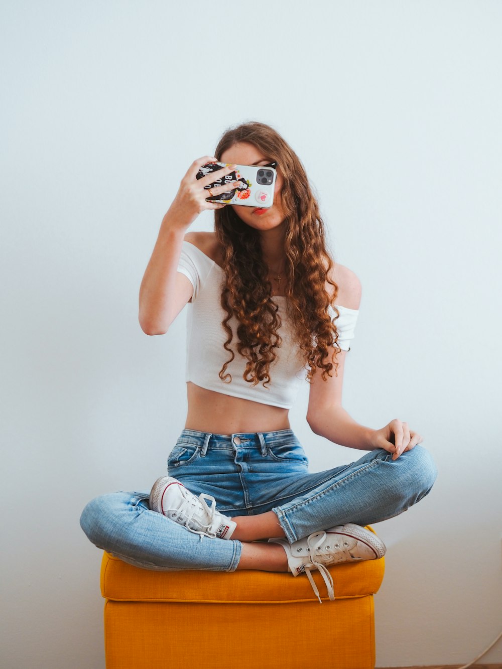 mulher na camisa rosa de manga comprida e jeans jeans azuis sentados no chão branco