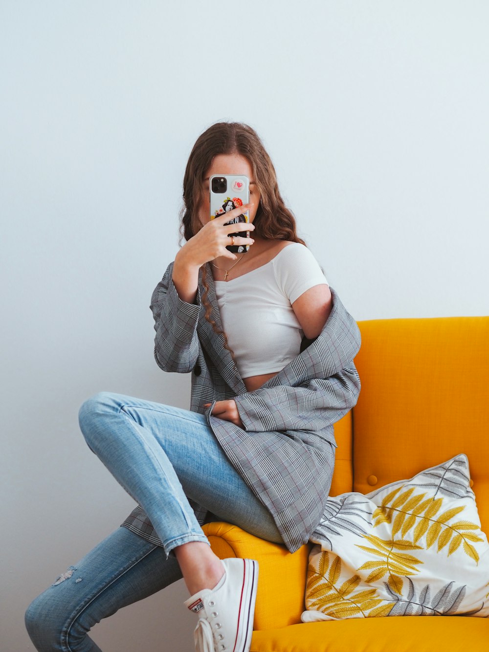 woman in gray cardigan and blue denim jeans sitting on yellow couch