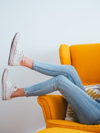 woman in blue denim jeans and white converse all star high top sneakers sitting on orange