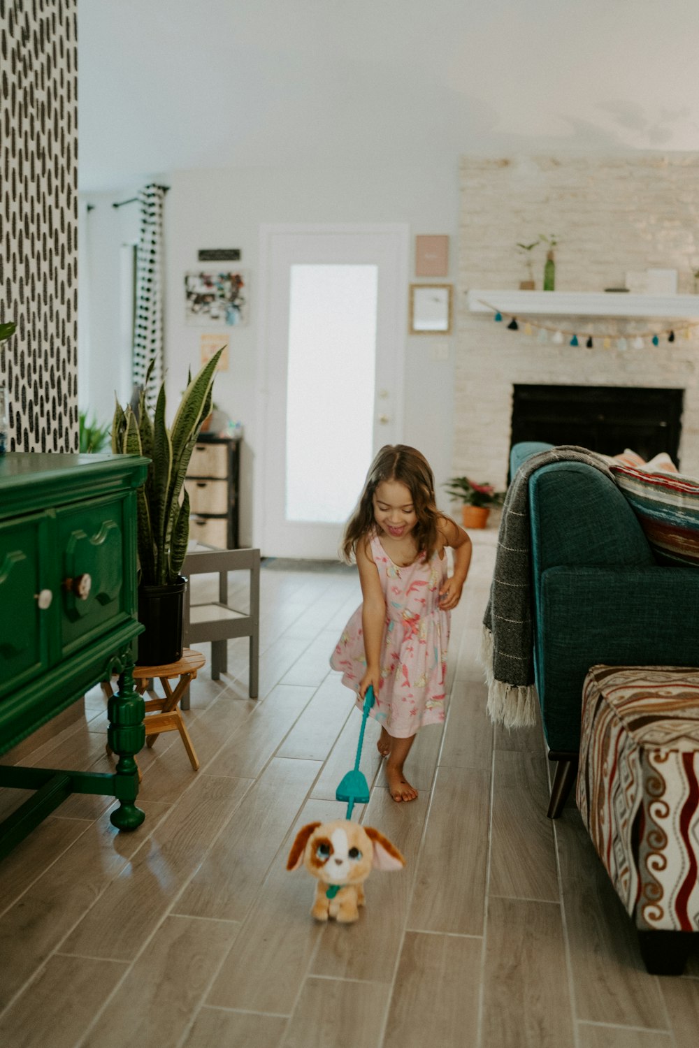 girl in pink dress standing beside green sofa chair