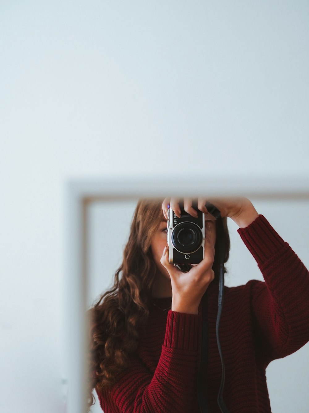 woman in red sweater holding black and silver camera