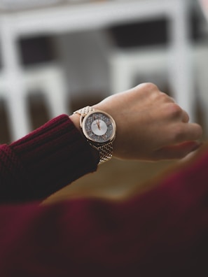 A wrist wearing the Lunamesh watch in soft pink with a delicate round dial against a cozy knitted sweater.