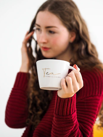 woman in red sweater holding white ceramic mug