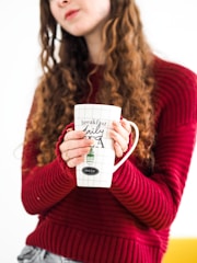 A warm, inviting scene of a person wearing a custom dog sweatshirt, holding a coffee mug featuring a doodle illustration.