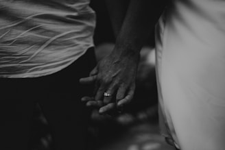 A touching black-and-white image of a couple holding hands during a ceremony.