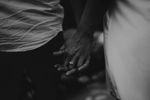 Black and white photo of a couple holding hands, focusing on intimate details