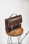 black leather sling bag on brown wooden round table