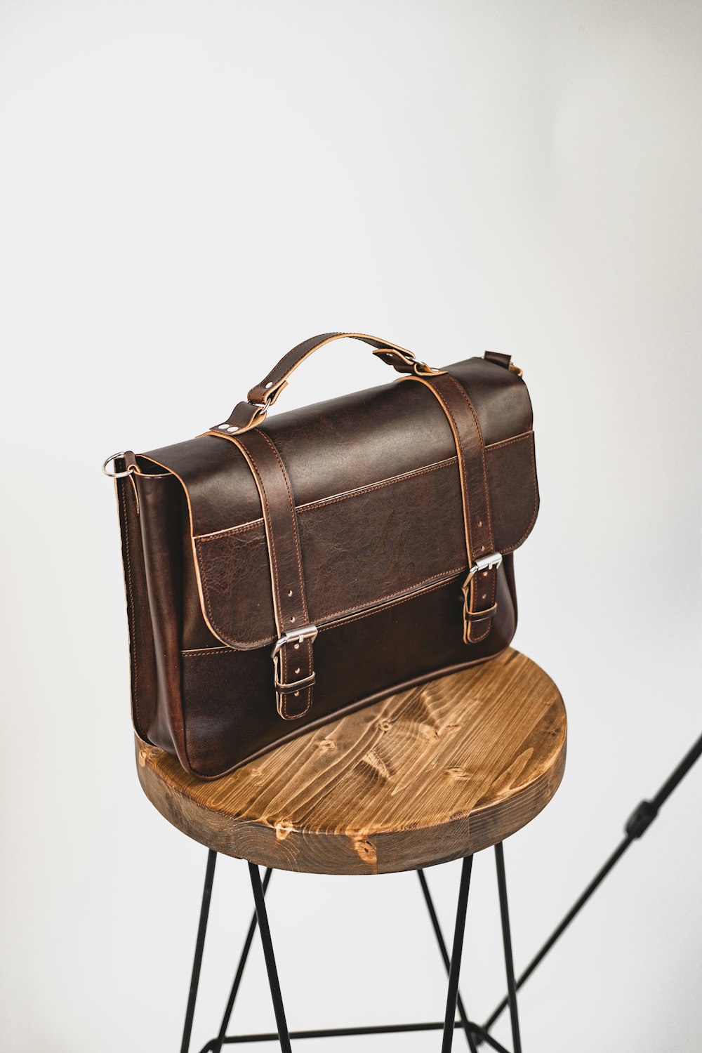 Sac à bandoulière en cuir noir sur table ronde en bois marron