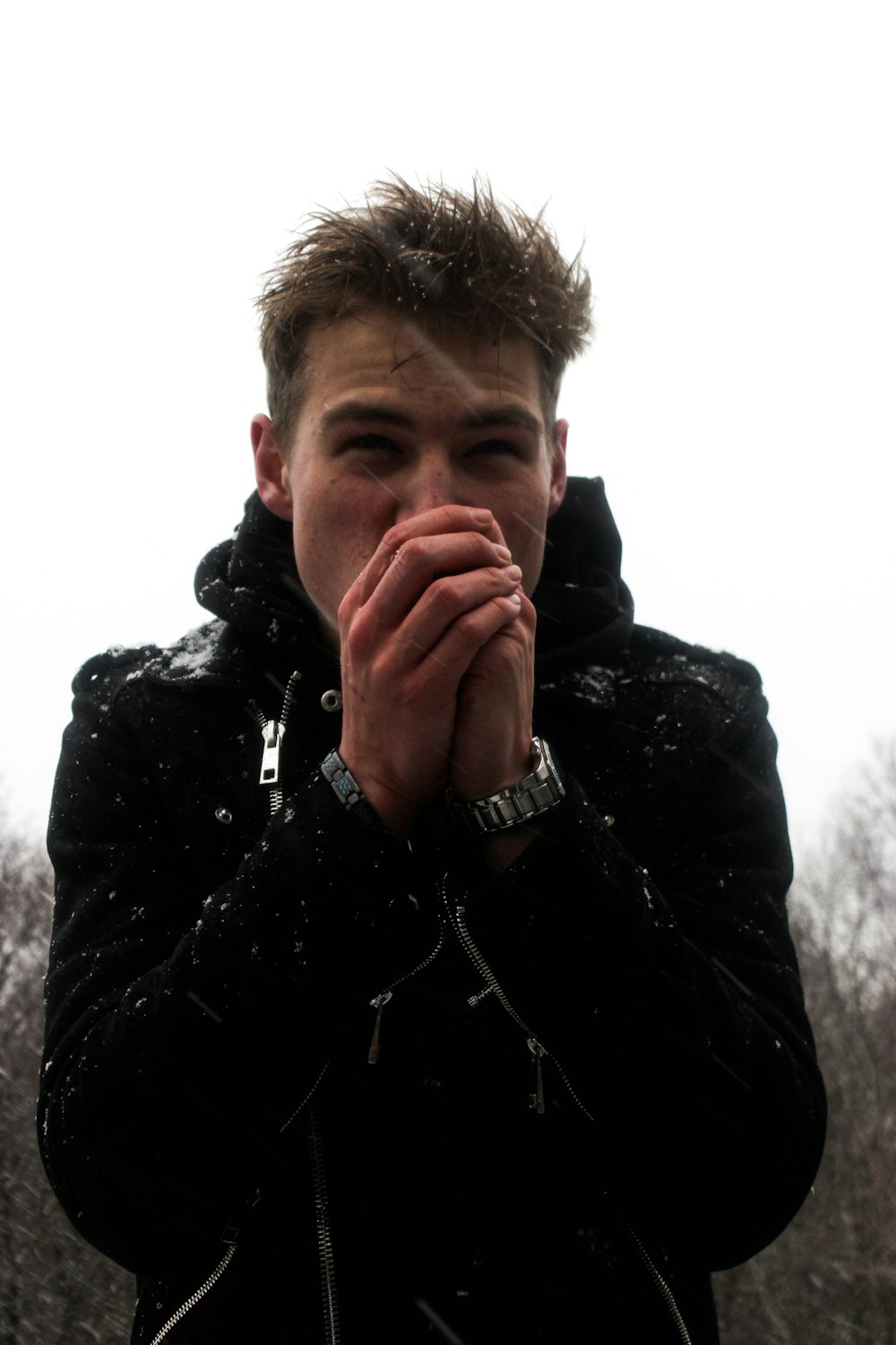 man in black jacket covering his mouth