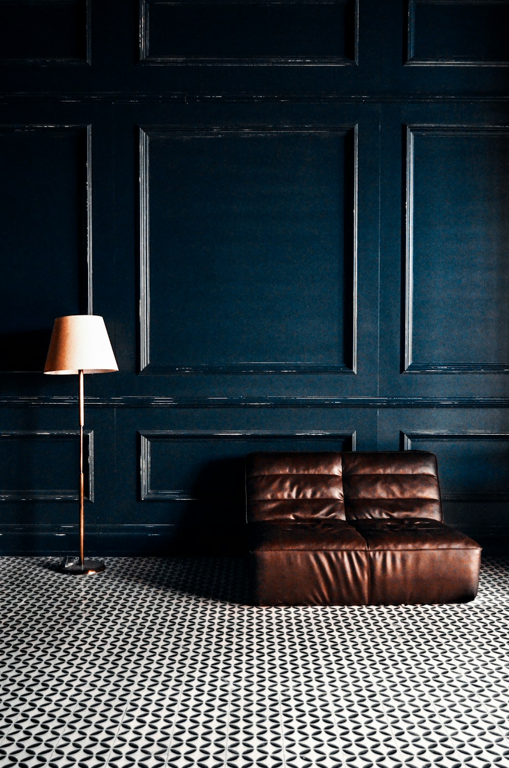 brown leather couch beside black wooden door