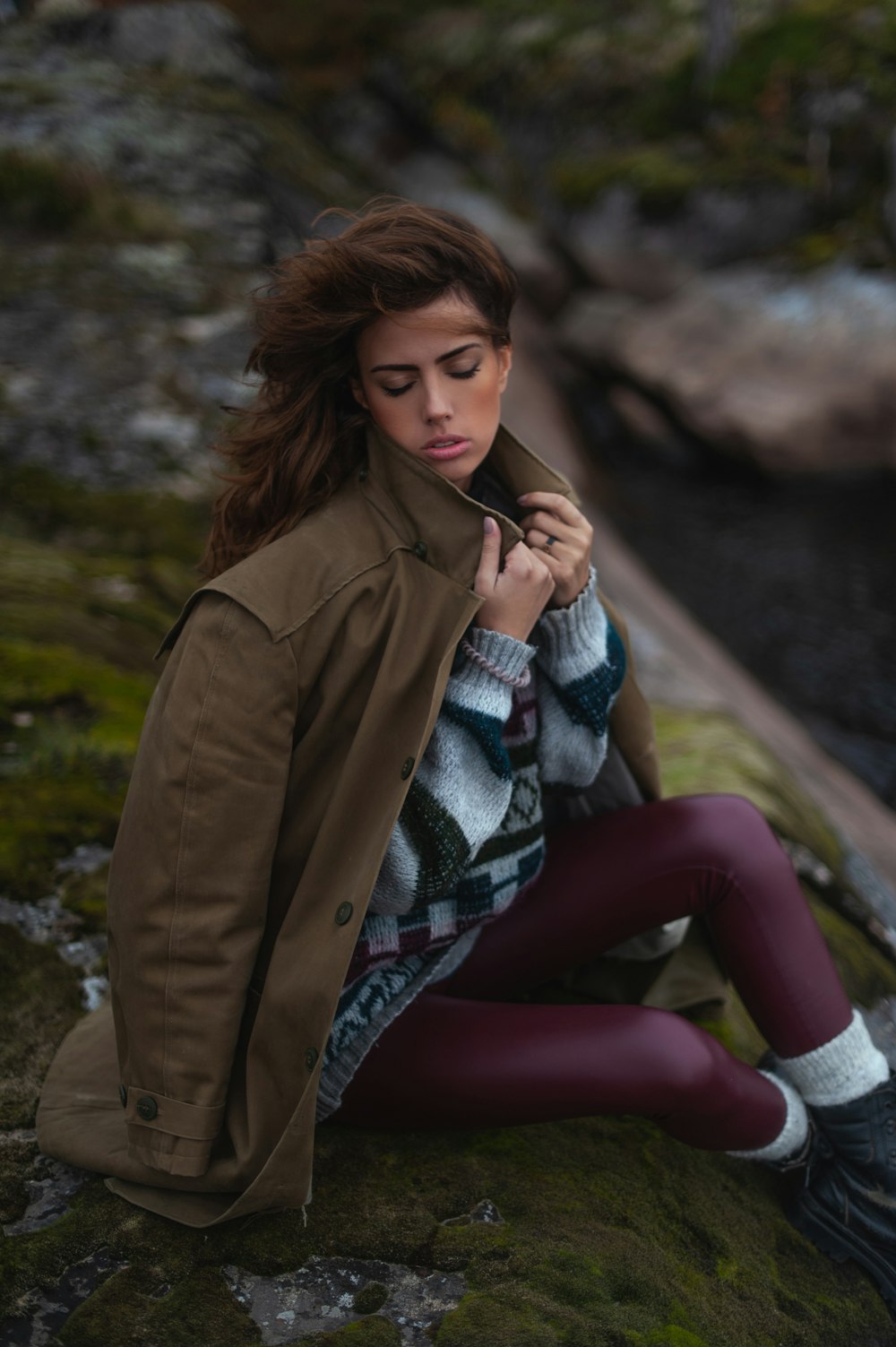 Femme en manteau marron assise sur le rocher