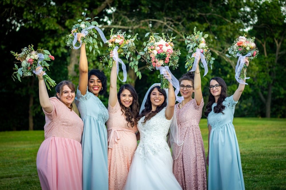 grupo de mulheres em vestidos cor-de-rosa segurando buquê de flores