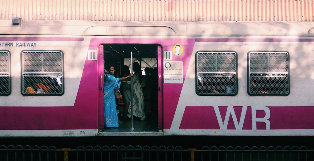 woman in blue denim jacket standing beside red and white train