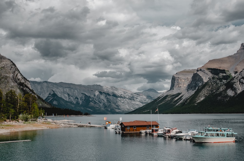 white and brown boat on body of water near mountain under white clouds during daytime