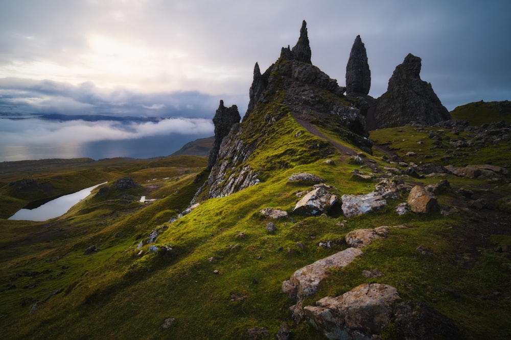 black castle on green grass covered hill under white cloudy sky during daytime