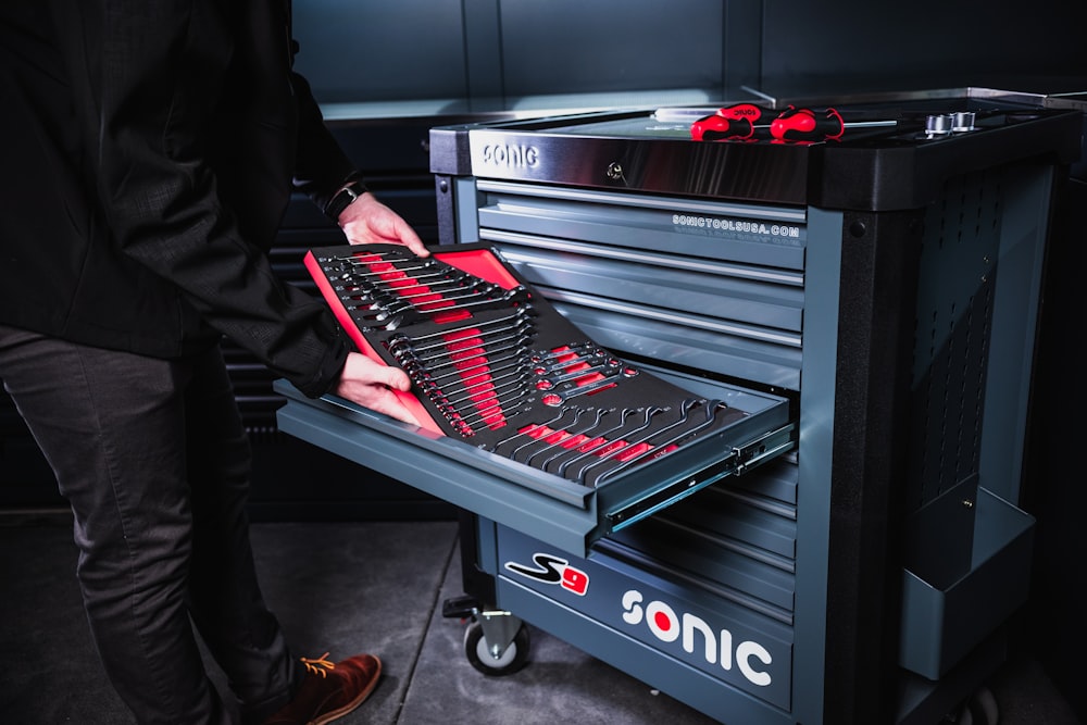 person in black pants and red shoes standing beside black and silver electric keyboard