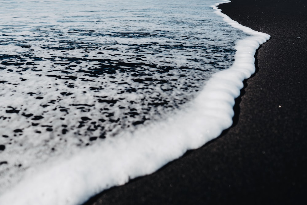 uma praia de areia preta com ondas que chegam à costa
