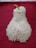 A mound of white rice is arranged in the shape of a pear with a green stem, placed on a textured, deep red fabric background.