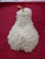 A mound of white rice is arranged in the shape of a pear with a green stem, placed on a textured, deep red fabric background.