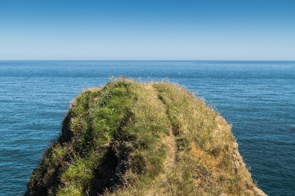 green and brown rock formation beside blue sea during daytime