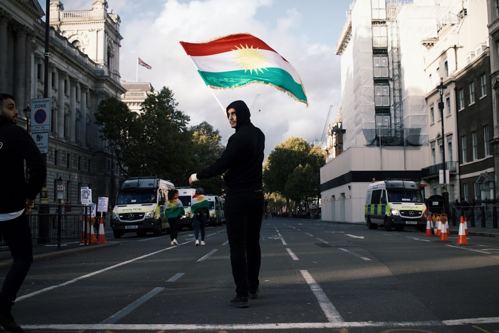 man in black suit holding red white and blue flag